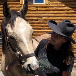 woman in a black cowboy hat with a horse