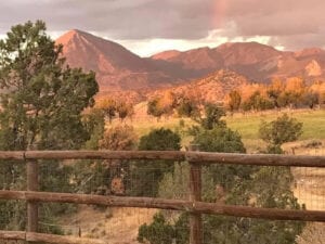 wooden log fence with mountain background and clouds